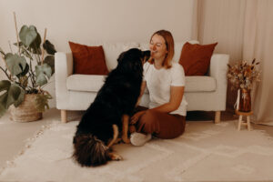 Psychologische Beraterin Melanie Staat sitzt mit einem Hund vor einem Sofa.