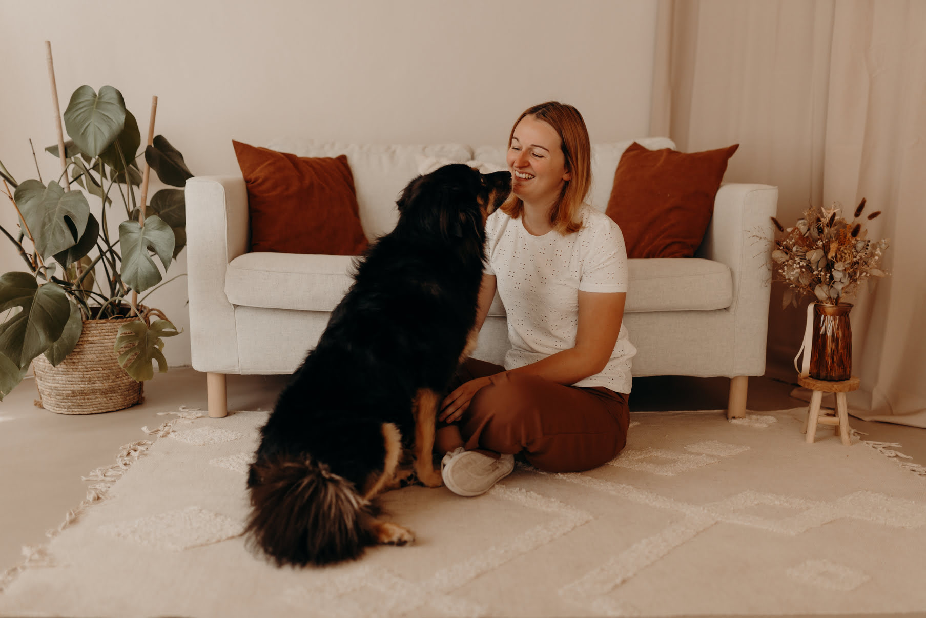 Psychologische Beraterin Melanie Staat sitzt mit einem Hund vor einem Sofa.